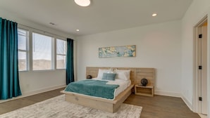A bedroom with a wooden bed, a white rug, a nightstand, and a painting on the wall. - 3 Story, Roof top very close to Broadway 516 (Nashville)