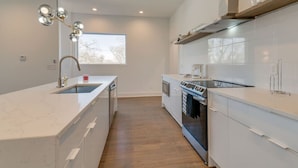 A modern kitchen with white cabinetry, a built-in oven, and a stainless steel range hood. - 3 Story, Roof top very close to Broadway 516 (Nashville)