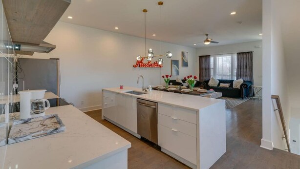 A modern kitchen with white cabinetry, a central island, and a dining area with a sofa and curtains. - 3 Story, Roof top very close to Broadway 516 (Nashville)