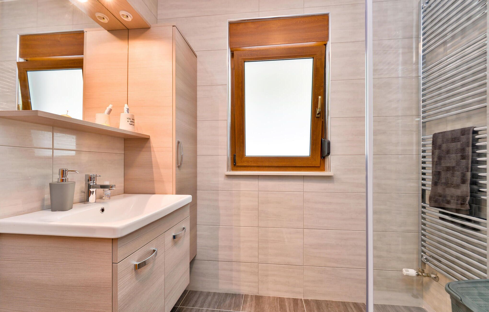 A modern bathroom with a vanity, a window, and a towel rack.