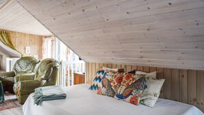 A cozy room with a bed, a green leather chair, and a wooden ceiling. - Beautiful apartment in Risør with WiFi (Risør)