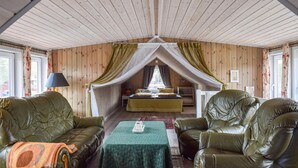 A cozy room with a bed, two leather sofas, a small table, and a canopy bed. - Beautiful apartment in Risør with WiFi (Risør)
