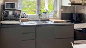 A modern kitchen with a built-in dishwasher, a sink, and a stove. - Beautiful apartment in Risør with WiFi (Risør)