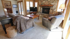Una sala de estar acogedora con chimenea de piedra, televisor y asientos cómodos.