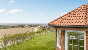 Een woonwijk met huizen, een grashelling en uitzicht op zee.