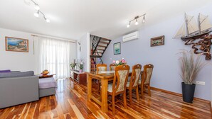 Un comedor con suelo de madera, una escalera y una mesa con sillas.