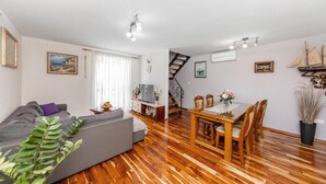 Una sala de estar moderna con sofá, mesa de comedor y sillas. Una escalera conduce a otro nivel.