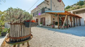 Un edificio de piedra con balcón, plantas en macetas y un patio de grava.