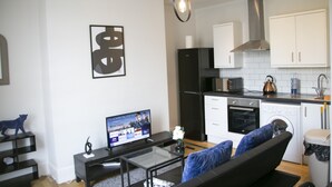 A modern kitchen with white cabinets, a black refrigerator, and a stainless steel range hood.