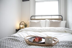 A neatly made bed with white linens, a tray with waffles and berries, and a cup of coffee on a woven tray. - Fortunae Boutique Apartment BY Fang (Sunderland)