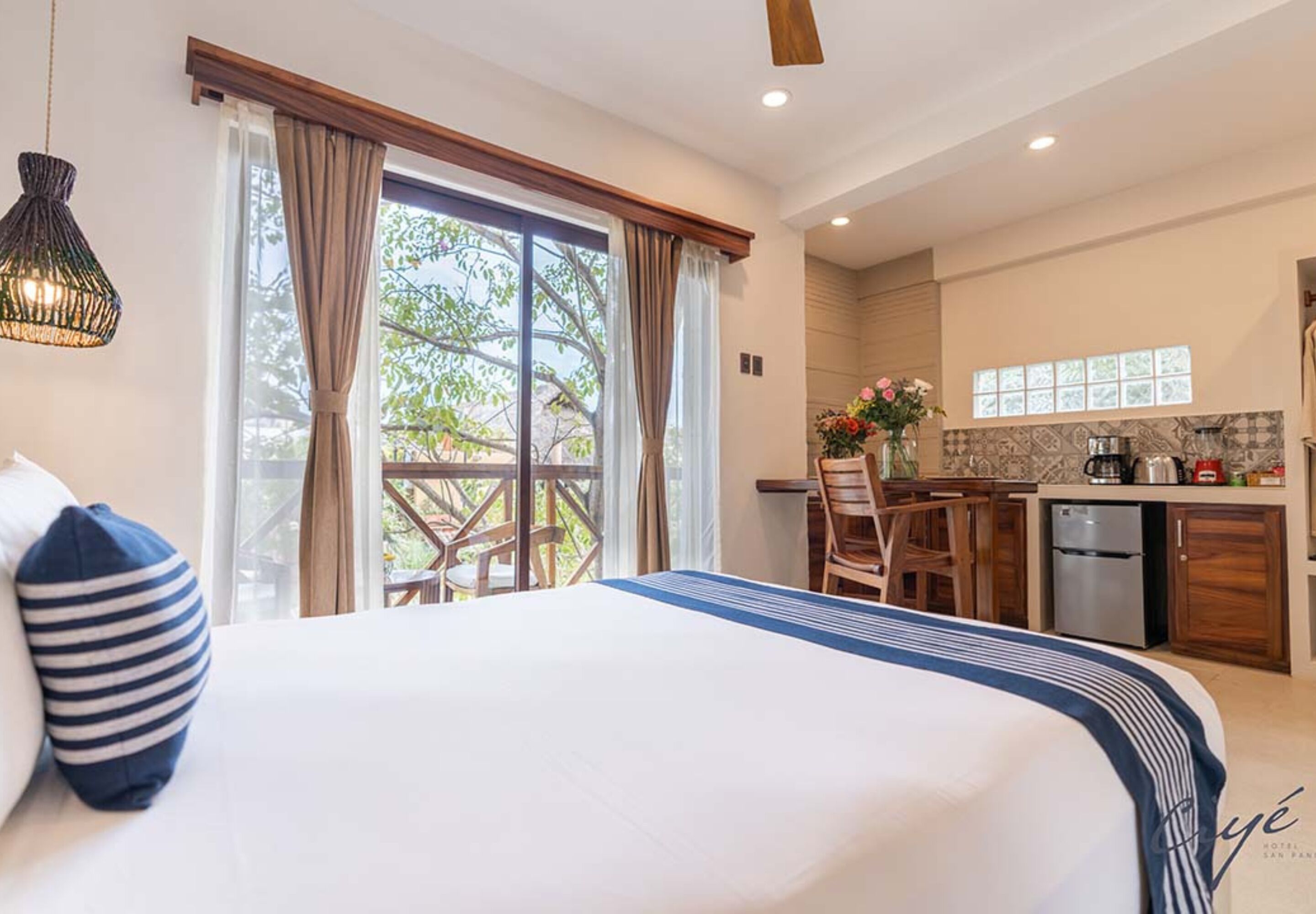 A hotel room with a large bed, a dining area, and a kitchen.