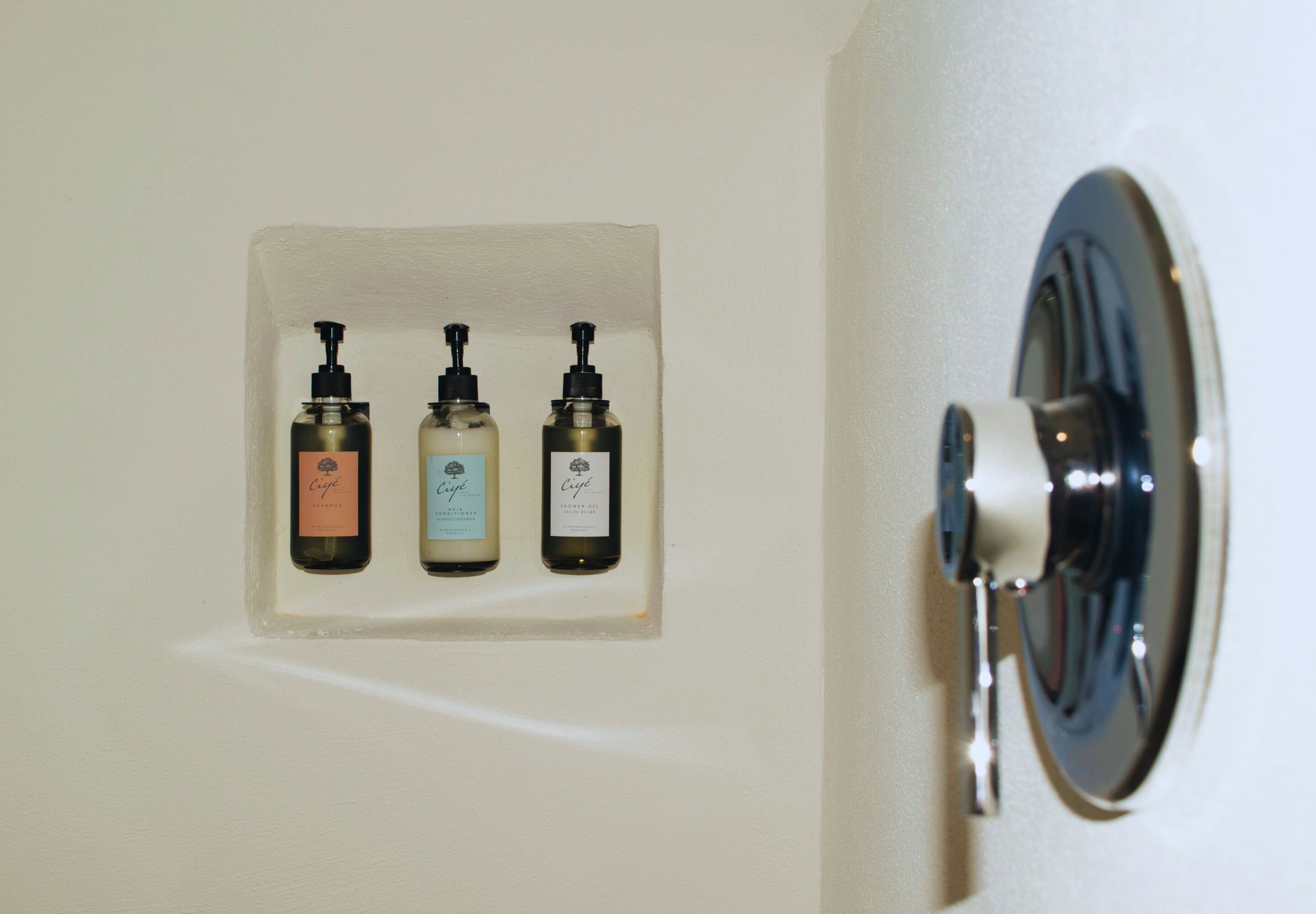 Un baño con tres dispensadores de jabón de manos montados en la pared.