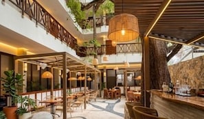 Ein mehrgeschossiges Innenraumambiente mit Sitzbereichen, einer Bar und hängenden Pflanzen.
