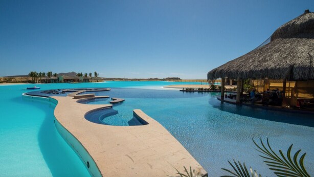 A resort pool with a thatched-roof structure and a clear blue sky. - Largest Terrace on the Ocean in Cabo! SUPER PENTHOUSE w/ 4,500 sq ft Terrace!! (Los Cabos)