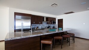 A modern kitchen with dark wood cabinets, stainless steel appliances, and a marble countertop. - Largest Terrace on the Ocean in Cabo! SUPER PENTHOUSE w/ 4,500 sq ft Terrace!! (Los Cabos)