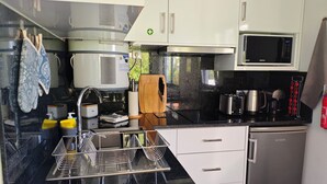 Une cuisine de taille réduite avec des meubles blancs, un plan de travail noir, un four à micro-ondes, un grille-pain et un évier.