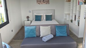 Une chambre à coucher moderne avec un lit, des tables de chevet, une commode, une bibliothèque et une fenêtre.