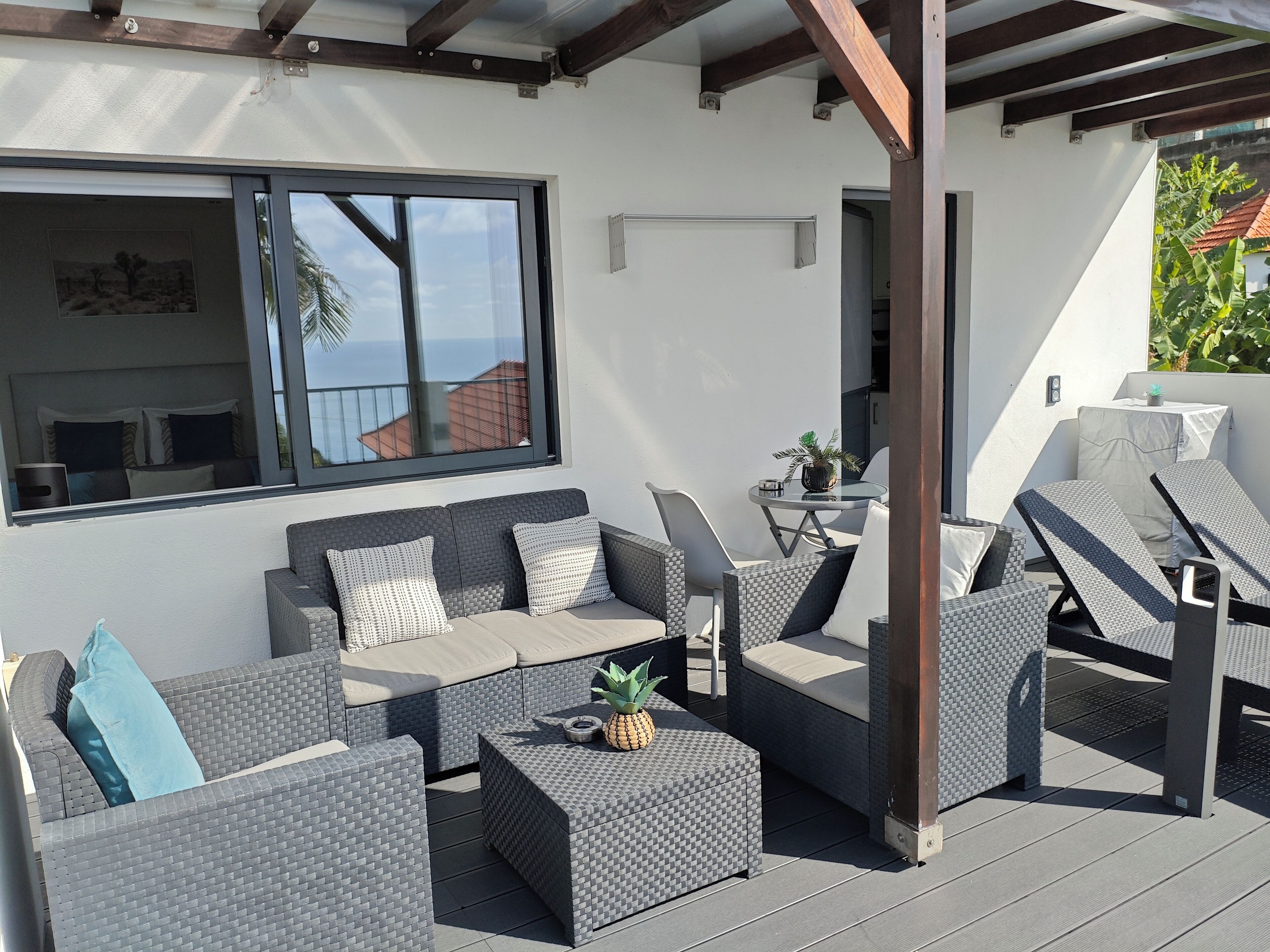 Un espace extérieur aménagé, abrité, avec un canapé, des chaises et une petite table.