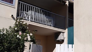 Ein Wohngebäude mit Balkon, Tor und kleinem Garten.