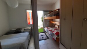 Ein gemütliches Schlafzimmer mit zwei Einzelbetten, einem Kleiderschrank und einem kleinen Fenster.