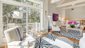 A spacious living room with large windows, a patterned rug, and a cozy seating area.