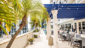 A rooftop terrace with outdoor seating, palm trees, and a pool.