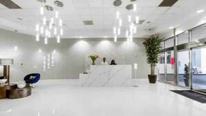 A modern reception area with a marble counter, hanging lights, and potted plants.