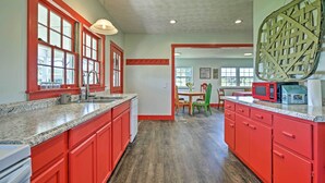 A kitchen with red cabinets, granite countertops, and a large window.