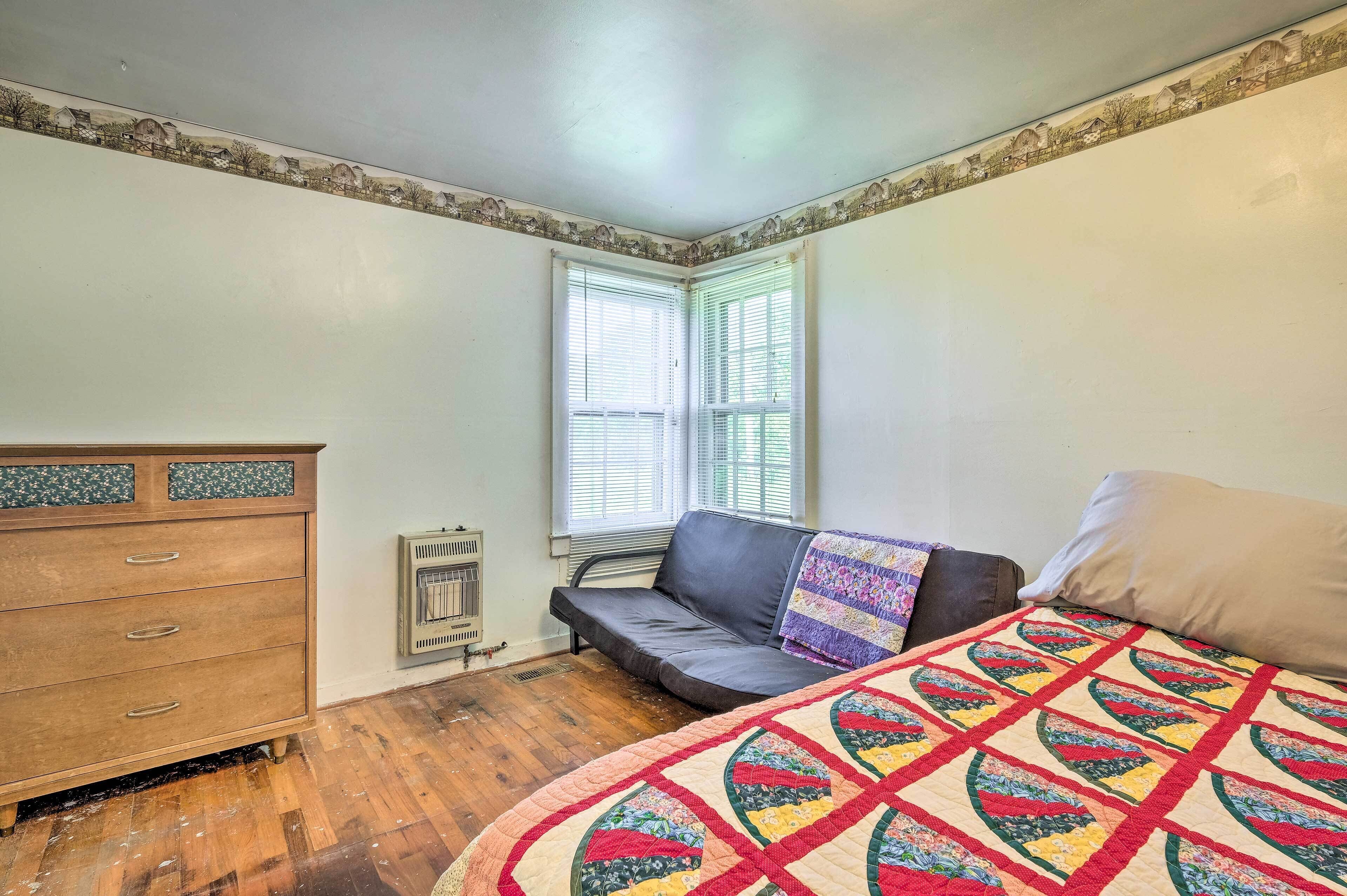 Une chambre à coucher avec une commode en bois, un canapé noir, une couvre-lit matelassé et un radiateur.