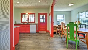 A kitchen with red cabinets, a white dishwasher, and a wooden dining table with chairs.