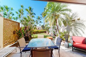 Relax in style with a glass-top table and comfortable seating amidst lush gardens and tropical plants.