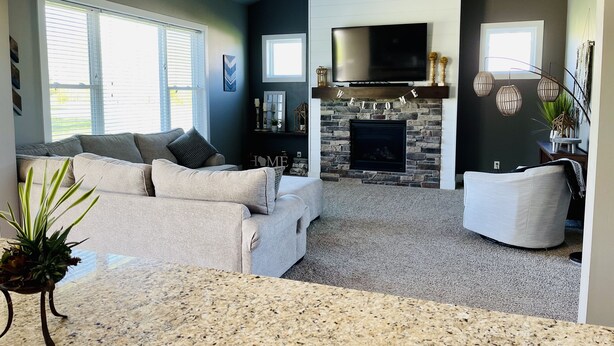 A modern living room with a stone fireplace, a flat-screen TV, and a ceiling fan. - EAA Air Venture Rental 4 Bedroom, Golf-Course Home (Winneconne)