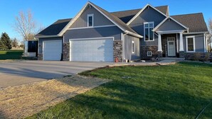 A two-story house with a garage, a stone exterior, and a well-maintained lawn. - EAA Air Venture Rental 4 Bedroom, Golf-Course Home (Winneconne)