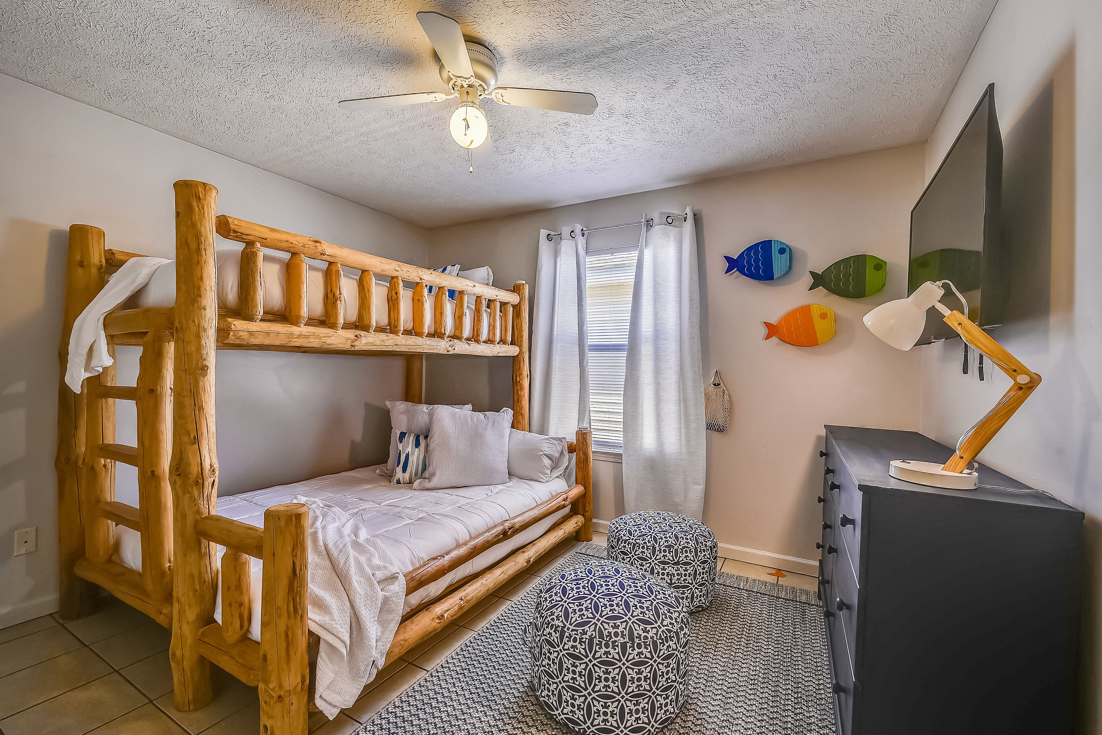 Ein Zimmer mit einem hölzernen Etagenbett, einem Schreibtisch mit Lampe und einer kleinen Fischdekoration an der Wand.