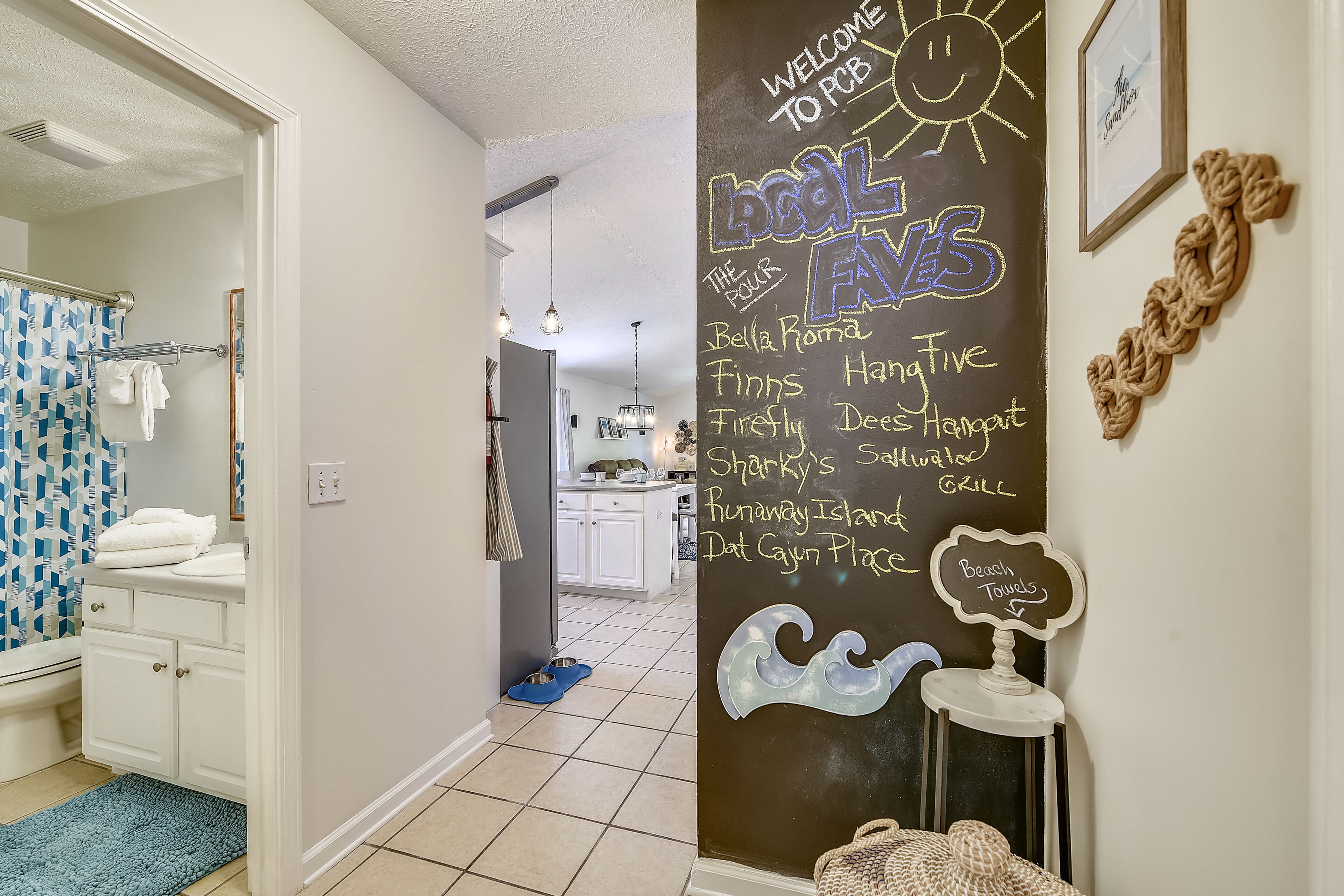 A bathroom with a blue patterned shower curtain, white cabinets, and a blue rug.