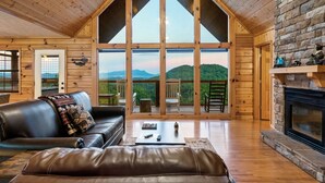 Un salon spacieux doté d’une grande fenêtre, d’une cheminée et offrant une vue sur les montagnes.