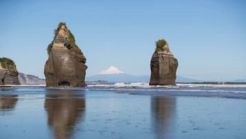 Une plage avec des formations rocheuses et une montagne qui se profile à l’horizon.