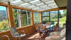 Un espace extérieur aménagé, abrité et doté de mobilier en bois et de grandes fenêtres offrant une vue panoramique.