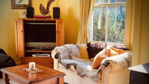 Una sala de estar acogedora con un sofá, una mesa de madera con una vela y un televisor en un mueble de madera.