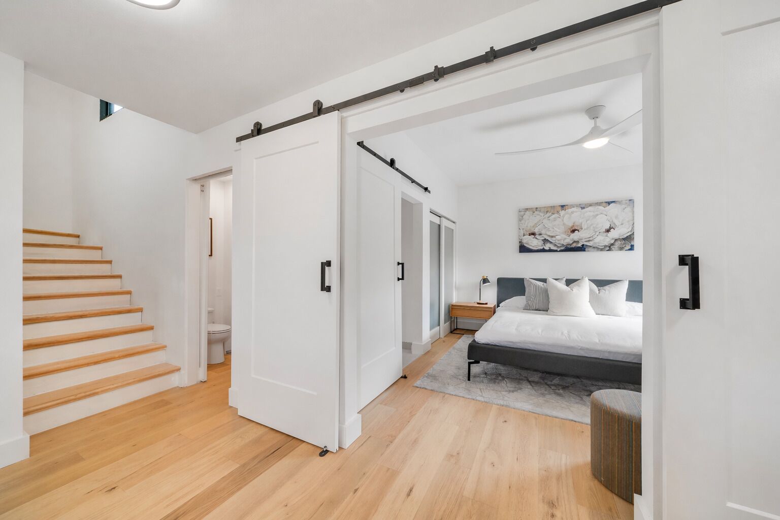 A modern bedroom with a bed, bedside table, and a painting on the wall.