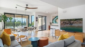 A spacious living room with a large TV, comfortable seating, and a balcony with a view. - Luxury Ocean View Kapalua Golf Villa, Walk to Kapalua Bay, 3BR/2BA (Lahaina)