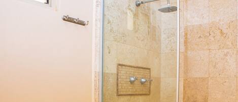 A bathroom with a toilet, a glass-enclosed shower, and beige tiled walls.