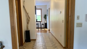 A hallway with a wooden staircase leading to a dining area.