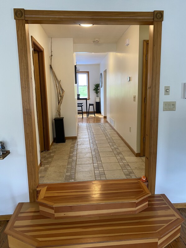 A hallway with a wooden staircase leading to a dining area.