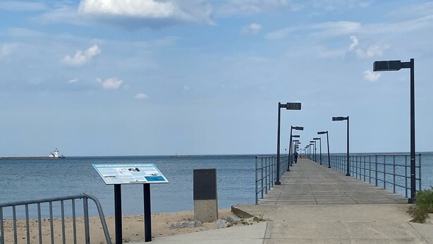 A concrete pier extending into a body of water with a signboard on the left.