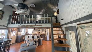 Een ruime loft-achtige woonruimte met een hoge nok, een entresol en een keuken met moderne apparatuur.