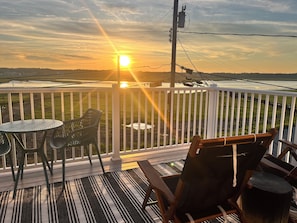 Eine Terrasse mit Tisch und Stühlen, mit Blick auf eine Landschaft bei Sonnenuntergang.