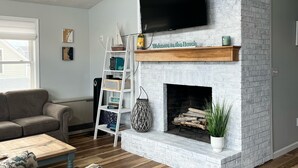 Un salon doté d’une cheminée, d’un téléviseur à écran plat et d’un ventilateur de plafond.
