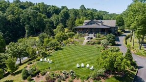 Une grande maison entourée d’une pelouse bien entretenue et d’arbres.
