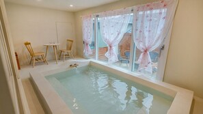 A room with a bathtub, two wooden chairs, a small table, and a window with curtains. - Gyeongju Nenugnam20 Hanok Pension (Gyeongju)